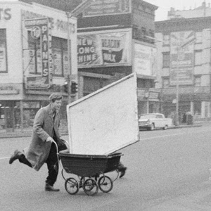 An artist in 1950s New York uses a wheelbarrow to carry his canvases.